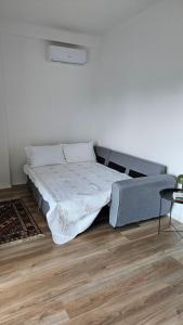 a bed in a white room with a wooden floor at Modern apartment with sea views in Vlorë