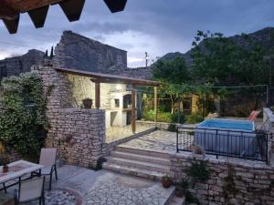 a stone house with a swimming pool and a patio at Villa Olive Old Qeparo in Qeparo