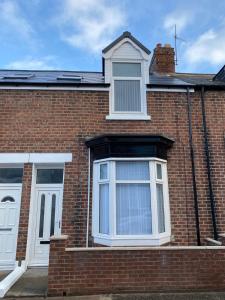 una casa de ladrillo con dos ventanas y puertas blancas en Apex Living NE - Beachville House II, en Sunderland
