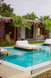 a pool with two beds and palm trees at SANIMAR By Mono Alex in Kassandra