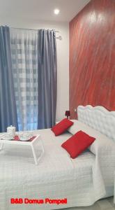 Un dormitorio con una cama blanca con almohadas rojas y una mesa. en Domus Pompeii, en Pompeya