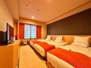 a room with three beds and a flat screen tv at Hotel Rose Garden Shinjuku in Tokyo
