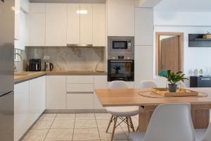 a kitchen with a wooden table and white cabinets at Island Memories Apartment in Ampavris