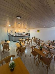 Un restaurante con mesas y sillas de madera y un mostrador. en Veleiro Hotel MCZ, en Maceió