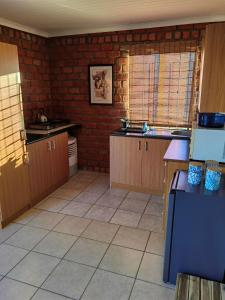 a kitchen with wooden cabinets and a brick wall at Daan Viljoen Self-Catering in Windhoek +7 photos