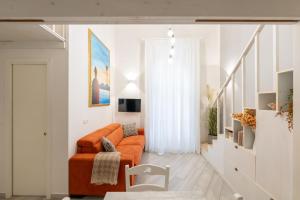 a living room with an orange couch and a chair at Appartamento Via Toledo 55 - Palazzo della Porta in Naples