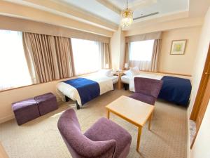 a hotel room with two beds and two chairs at Hotel Rose Garden Shinjuku in Tokyo