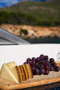a plate of cheese and grapes on a cutting board at Mallorcainblue Charter in Port d'Alcudia