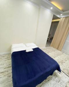 ein Schlafzimmer mit einem blauen Bett mit zwei Handtüchern darauf in der Unterkunft Business class apartment EXPO in Astana