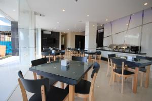 une salle à manger avec des tables et des chaises noires dans l'établissement OS Hotel Airport Batam, à Batam Center