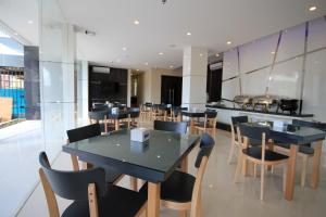 a dining room with black tables and chairs at OS Hotel Airport Batam in Batam Center