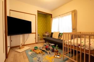 a baby room with a crib and a television at FIKA - Komorebi in Furano