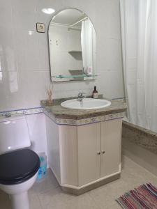 a bathroom with a sink and a toilet and a mirror at El apartamento de arriba in Cedeira +8 photos