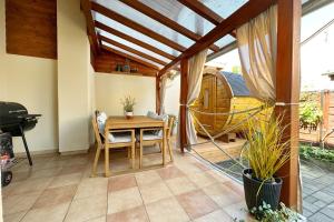 een patio met een tafel en stoelen en een hangmat bij Dora Holiday House & Apartments in Keszthely
