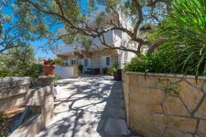 a house with a tree in the middle of a sidewalk at Relaxing Beach holiday house in Hvar