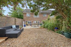 Un patio trasero con un sofá negro y una casa de ladrillo. en Quiet Mews House with PARKING and GARDEN close to centre and beach, en Brighton & Hove