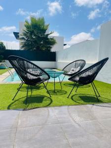 dos sillas y una mesa en el césped en Villa Neo - Piscina privada - 8 minutos de Corralejo, mini Gym!!, en Villaverde