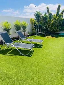 dos sillas sentadas en el césped en un patio en Villa Neo - Piscina privada - 8 minutos de Corralejo, mini Gym!!, en Villaverde
