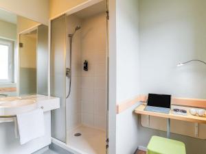ein Badezimmer mit Dusche und einem Laptop auf einem Schreibtisch in der Unterkunft Ibis Budget Bilbao Barakaldo in Barakaldo