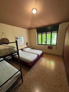 Un dormitorio con dos camas y una ventana. en Villa Pineta - Parcheggio, Giardino, Wi-Fi, Tavolo Ping Pong - Oasi di Tranquillità a Due Passi dal Mare, en Lignano Sabbiadoro