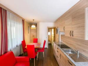 a kitchen with red chairs and a dining table at Amazing apartment house Diamant with breathtaking view in Santa Cristina in Val Gardena +29 photos