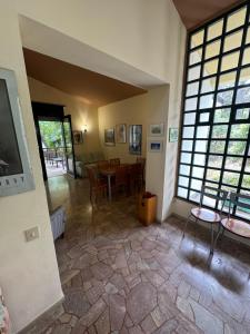 Una sala de estar con mesa y sillas y ventanas. en Villa Pineta - Parcheggio, Giardino, Wi-Fi, Tavolo Ping Pong - Oasi di Tranquillità a Due Passi dal Mare, en Lignano Sabbiadoro