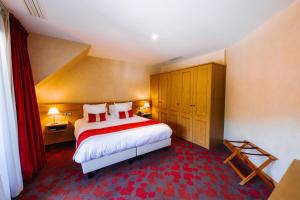 a bedroom with a large bed with red and white pillows at Les Violettes Hotel & Spa in Jungholtz