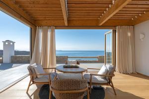 a living room with a table and chairs and a view of the ocean at Villa Casa Spilia in Mýkonos City