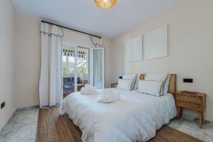 a large white bed in a room with a window at New Renovated Front Line Beach Playa Rocio Puerto Banus in Marbella +49 photos