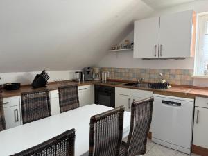 a kitchen with white cabinets and a table and chairs at Ferienwohnung Zellerfelder Höhe in Clausthal-Zellerfeld