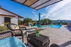 Un patio con sillas y una mesa y una piscina. en VILA OLIVE TREE Krk, en Kornić
