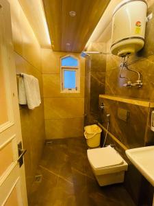 a bathroom with a toilet and a sink and a window at Hotel Kufri Holiday Inn in Kūfrī +52 photos