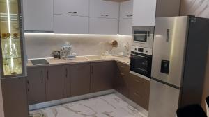 a kitchen with white cabinets and a stainless steel refrigerator at Apartment Tuthon in Pomorie