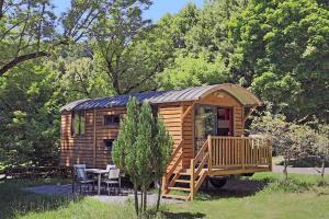 a wooden cabin with a deck and a table and chairs at LES ROULOTTES DU MOULIN in Confort