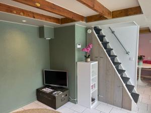 a living room with a staircase and a tv at Guesthouse West in Noordwijk