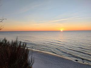 a sunset over the ocean on a beach at Róża Wiatrów Leśny Klif 2 in Debina