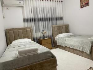 a bedroom with two beds and a window with curtains at Kriss APARTMENT in Përmet