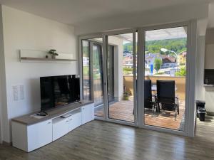 a living room with sliding glass doors and a television at Ferienwohnung am Schlosspark in Altmünster