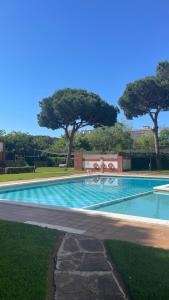 a swimming pool in a park with trees in the background at Maravilloso apartamento Delux in Blanes