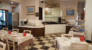 a restaurant with tables and chairs and a kitchen at Hotel Marietta in Caorle