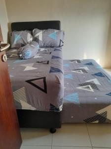 ein Bett mit einer Bettdecke und Kissen darauf in der Unterkunft Nita's Sweet Apartment Gunawangsa Manyar 2BR - close to Unair Galaxy Mall in Surabaya