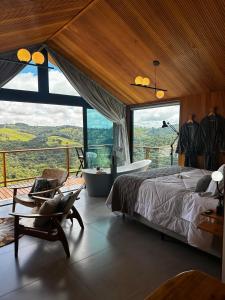 a bedroom with a bed and a balcony with a tub at Cabana Nórdica com Maravilhosa Vista da Serra in Gonçalves