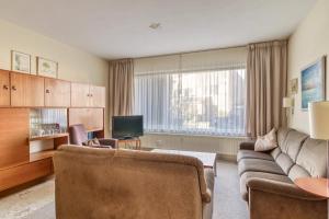 a living room with a couch and a tv at Appartement in Cadzand