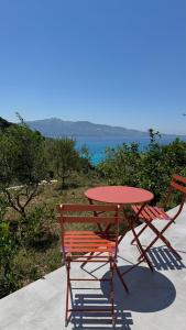 a red table and two chairs sitting next to a table and a table and chairs at Vila Bedro in Sarandë