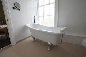 a white bath tub in a bathroom with a window at RainHill Hall Hotel in Rainhull