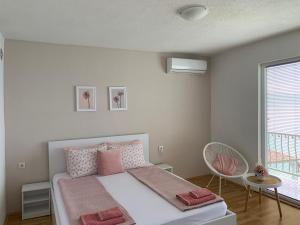 a bedroom with a bed with pink pillows and a window at Apartment Polkaposki Trpejca in Trpejca