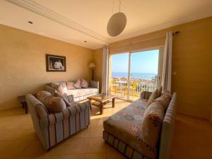 ein Wohnzimmer mit zwei Sofas und einem großen Fenster in der Unterkunft A5 Bel Appartement vue mer a 300m de la plage in Agadir