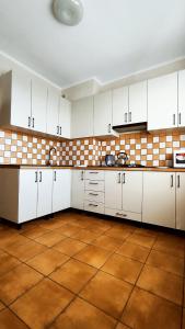 Una cocina con gabinetes blancos y piso de baldosas. en Василя Стуса 10 City Rooms, en Bila Tserkva