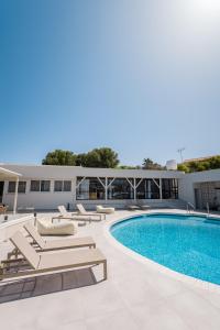a swimming pool with chaise lounges next to a building at Rose of Crete in Plataniás