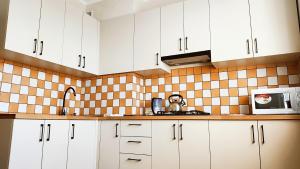 a kitchen with white cabinets and a microwave at Василя Стуса 10 City Rooms in Bila Tserkva